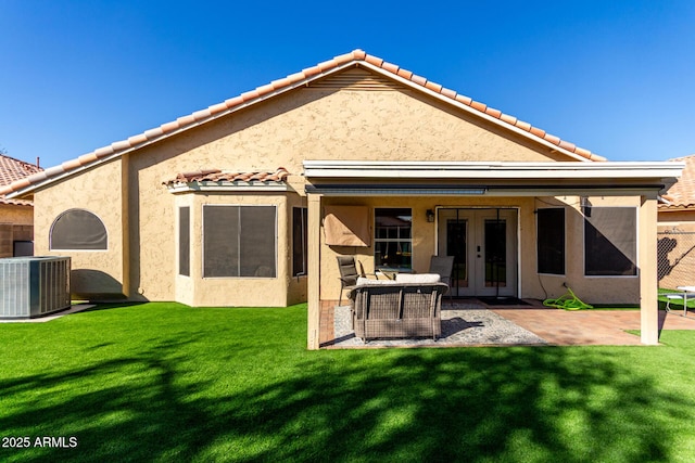 rear view of property featuring french doors, stucco siding, a yard, and central air condition unit