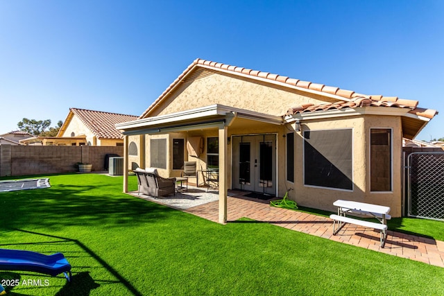 back of property with french doors, stucco siding, a lawn, a patio area, and a fenced backyard