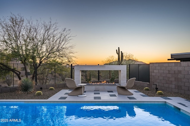 view of swimming pool featuring an outdoor fire pit, a patio area, fence, and a fenced in pool