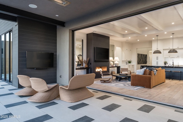 living room featuring an accent wall, recessed lighting, a large fireplace, and beamed ceiling