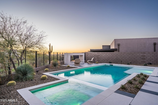 pool at dusk featuring a patio area, a fenced backyard, a fenced in pool, and an in ground hot tub