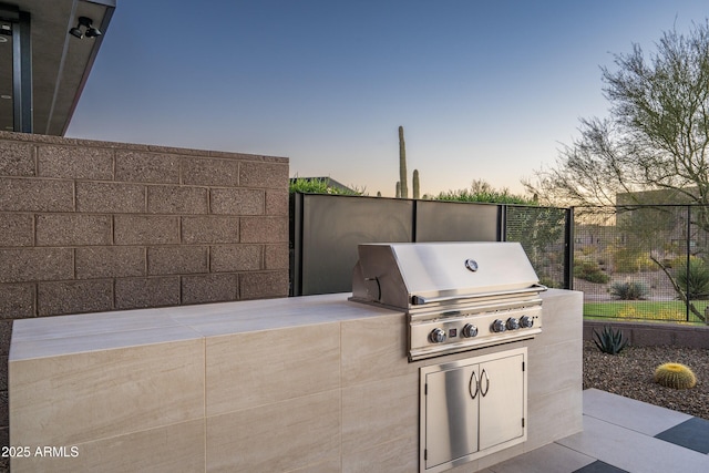 view of patio featuring a grill, fence, and an outdoor kitchen