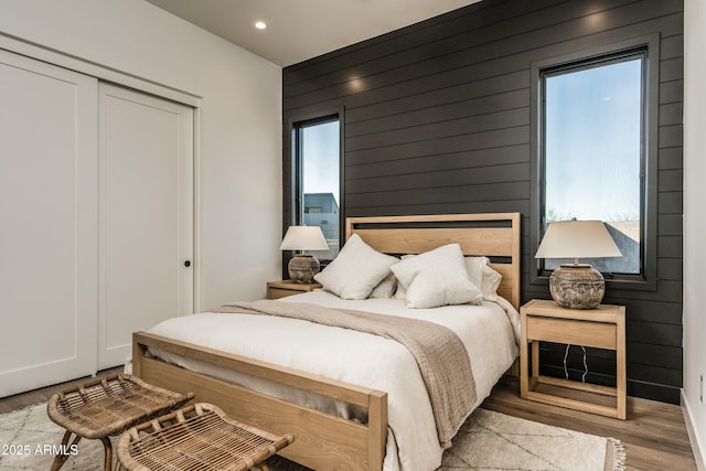 bedroom featuring recessed lighting, a closet, wooden walls, and wood finished floors