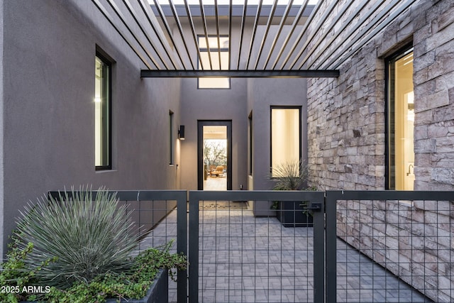 doorway to property with stone siding, fence, a gate, and stucco siding