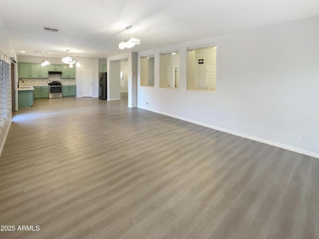 unfurnished living room featuring wood-type flooring, sink, and a notable chandelier