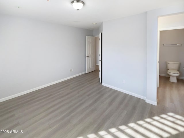 unfurnished bedroom featuring ensuite bathroom and light hardwood / wood-style flooring