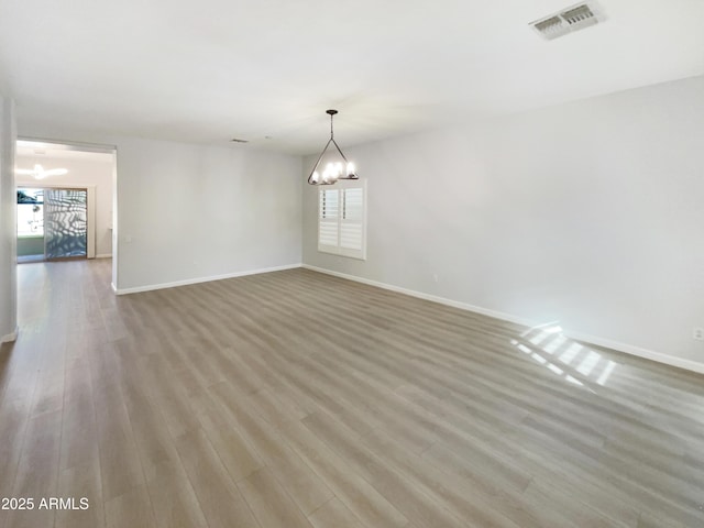 unfurnished room featuring a chandelier and light wood-type flooring