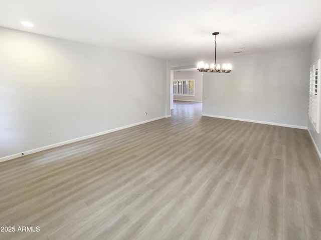 empty room featuring an inviting chandelier and light hardwood / wood-style flooring