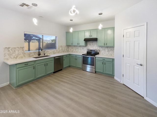 kitchen featuring sink, appliances with stainless steel finishes, hanging light fixtures, green cabinetry, and light wood-type flooring