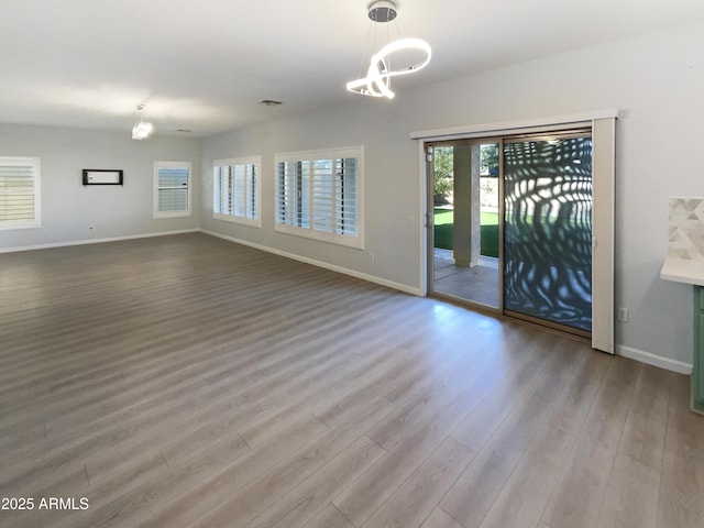 empty room featuring a chandelier and light wood-type flooring