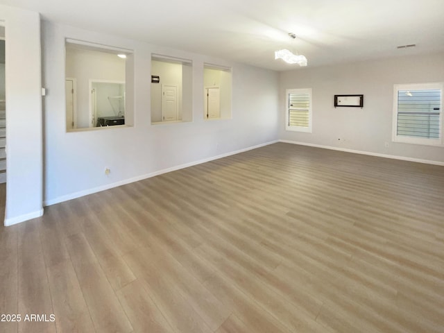 empty room with wood-type flooring and a chandelier