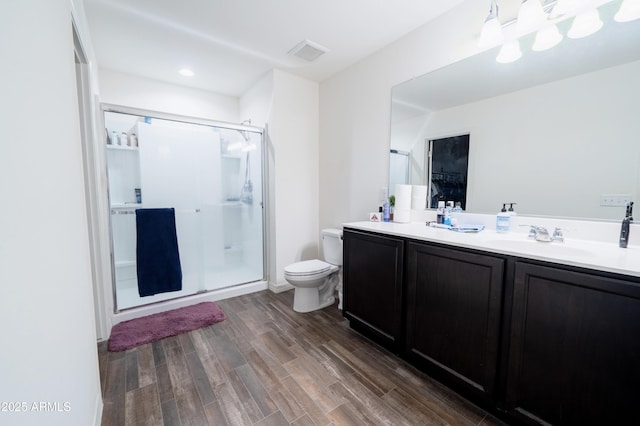 bathroom featuring hardwood / wood-style floors, vanity, a shower with shower door, and toilet