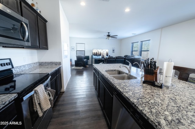 kitchen featuring sink, ceiling fan, light stone counters, appliances with stainless steel finishes, and dark hardwood / wood-style flooring