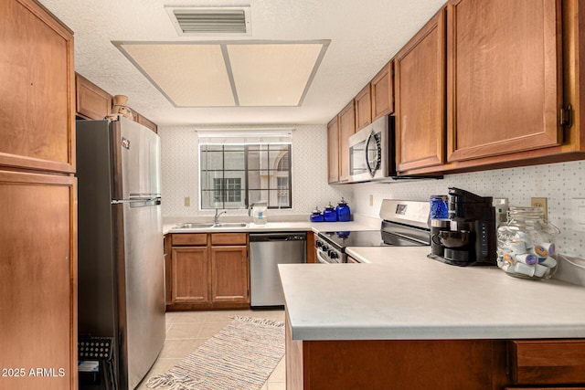 839 S Westwood Unit 287, Mesa, AZ 85210 - kitchen featuring stainless steel appliances, a sink, brown cabinetry, light countertops, and wallpapered walls