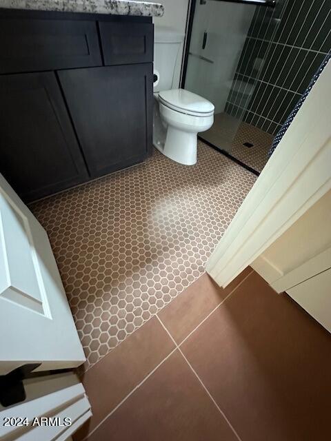 bathroom with toilet, tile patterned floors, and tiled shower