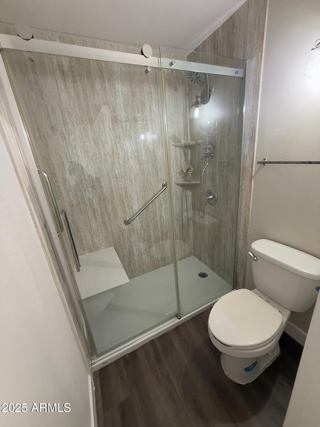 bathroom featuring hardwood / wood-style flooring, a shower with door, and toilet