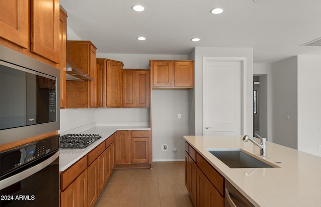 kitchen with light stone countertops, appliances with stainless steel finishes, sink, light tile patterned floors, and ventilation hood