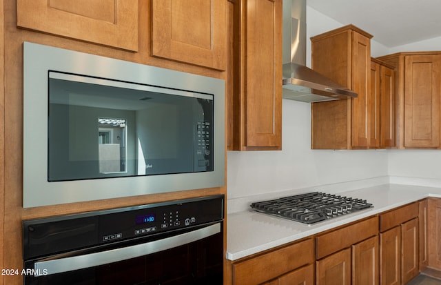 kitchen with wall chimney exhaust hood and stainless steel appliances