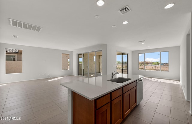 kitchen featuring stainless steel dishwasher, sink, an island with sink, and light tile patterned floors