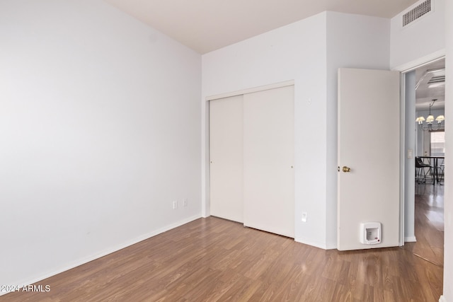 unfurnished bedroom with a closet, hardwood / wood-style floors, and a chandelier