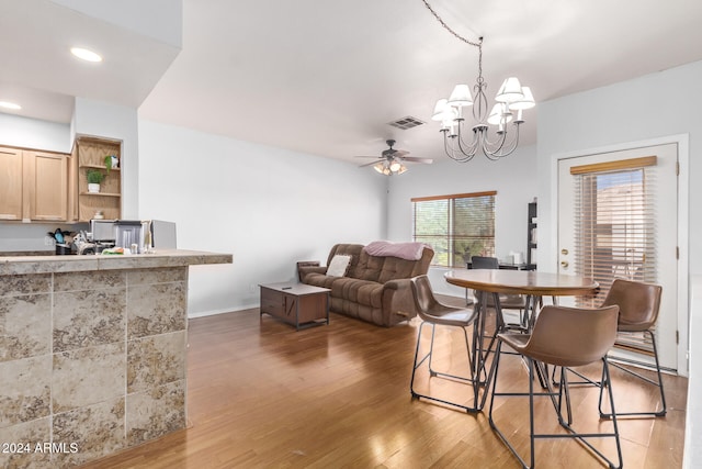 dining area featuring wood-type flooring and ceiling fan with notable chandelier