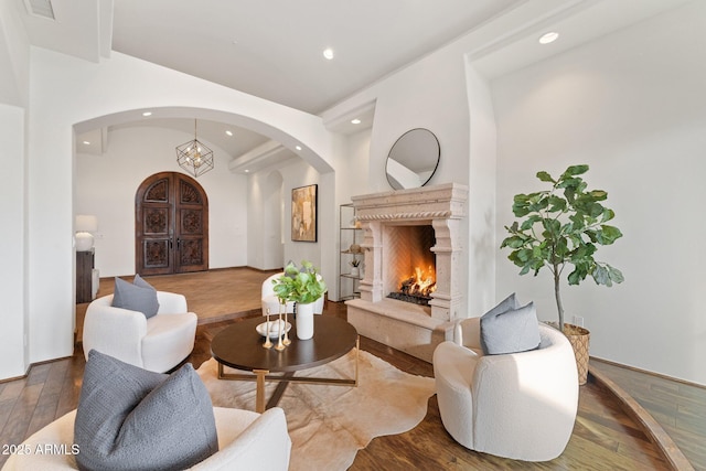 living area with an inviting chandelier, a fireplace, and hardwood / wood-style floors