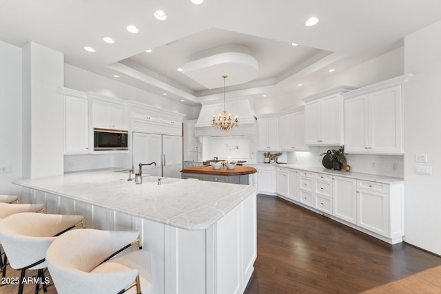 kitchen featuring white cabinetry, kitchen peninsula, a raised ceiling, and built in appliances