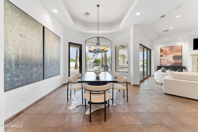 dining area with a raised ceiling and a notable chandelier