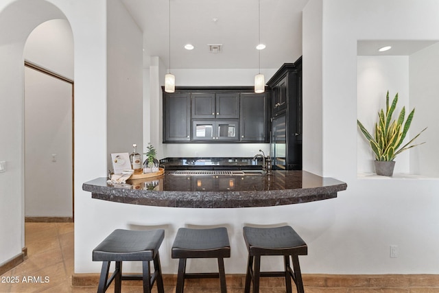 kitchen with a kitchen breakfast bar, pendant lighting, light tile patterned floors, and kitchen peninsula