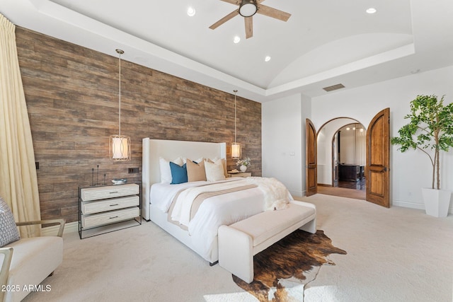 bedroom with vaulted ceiling, ceiling fan, light carpet, and wood walls