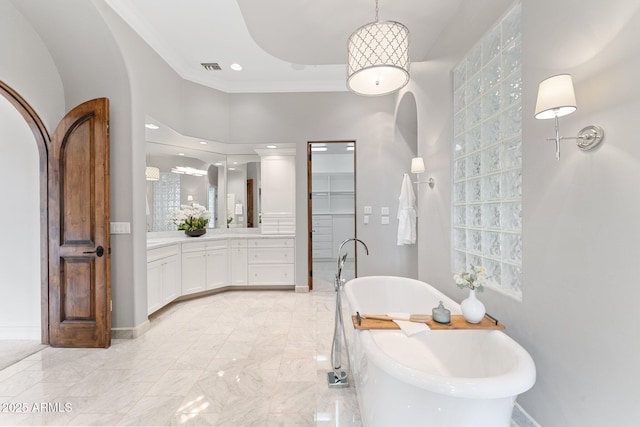 bathroom featuring ornamental molding, vanity, and a bathing tub