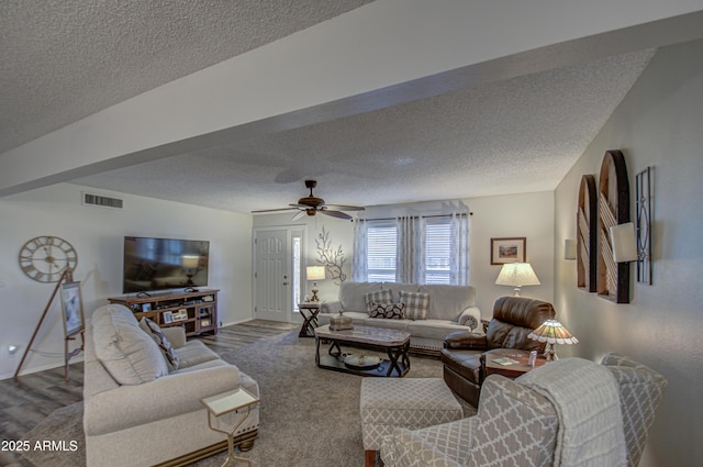 living room with a textured ceiling, ceiling fan, and carpet