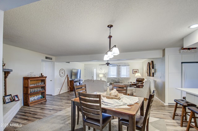 dining space featuring a textured ceiling, ceiling fan, and hardwood / wood-style floors