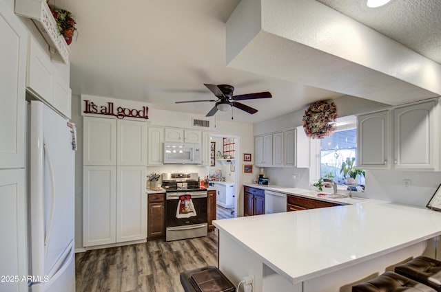 kitchen featuring white appliances, kitchen peninsula, a breakfast bar, and white cabinetry