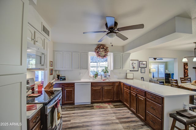 kitchen with white appliances, kitchen peninsula, white cabinets, and dark brown cabinets