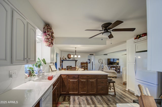 kitchen with white fridge, dishwasher, a breakfast bar area, kitchen peninsula, and sink