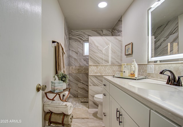 bathroom featuring toilet, tiled shower, and vanity