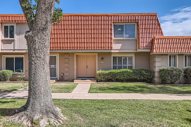townhome / multi-family property with a front lawn, mansard roof, and a tile roof