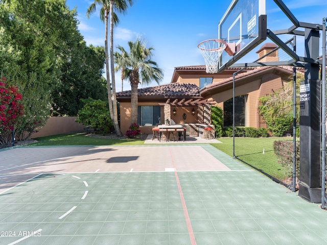 view of sport court with basketball hoop, a yard, and fence