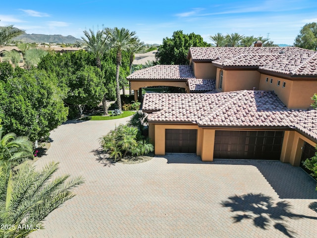 view of front of property featuring a tile roof, a mountain view, an attached garage, and stucco siding