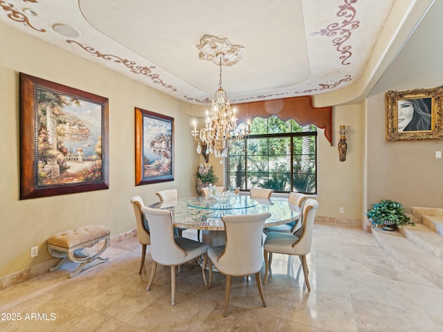 dining area featuring a tray ceiling, baseboards, and an inviting chandelier