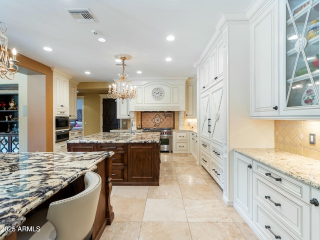 kitchen featuring visible vents, glass insert cabinets, decorative light fixtures, and light stone countertops