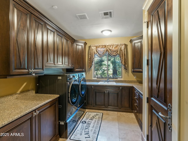 washroom with cabinet space, a sink, visible vents, and separate washer and dryer