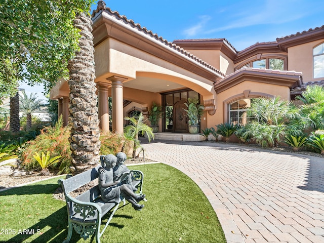 exterior space with a tiled roof, a front lawn, and stucco siding