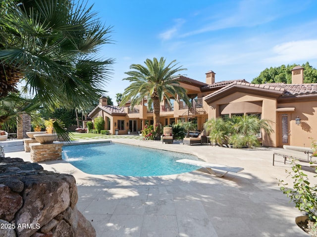 outdoor pool featuring a diving board and a patio