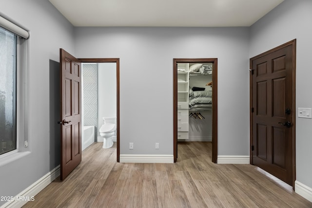 5740 N Casa Blanca Dr, Paradise Valley, AZ 85253 - unfurnished bedroom featuring baseboards, a closet, a spacious closet, ensuite bath, and light wood-style flooring