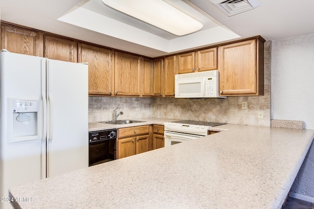 kitchen with sink, a raised ceiling, kitchen peninsula, white appliances, and decorative backsplash