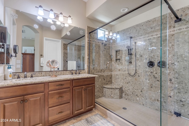 bathroom featuring a shower with door, double sink vanity, and tile patterned flooring