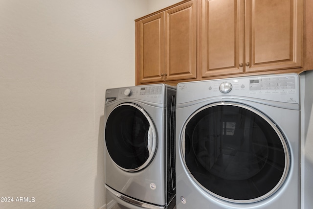 clothes washing area featuring washing machine and clothes dryer and cabinets