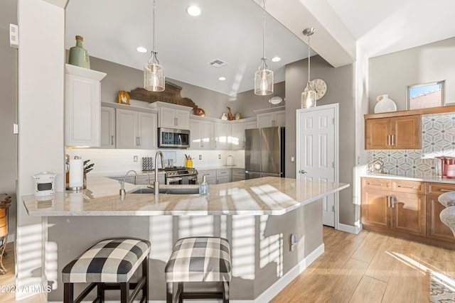 kitchen featuring appliances with stainless steel finishes, decorative light fixtures, kitchen peninsula, and white cabinets